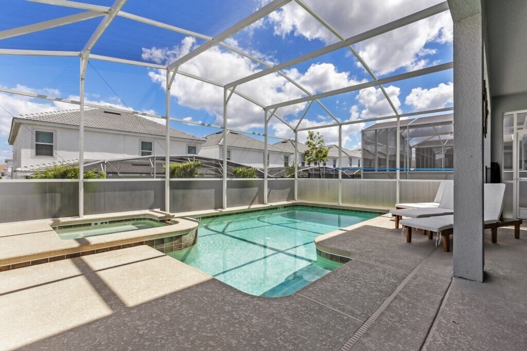 A covered outdoor swimming pool with lounge chairs and a view of residential buildings.