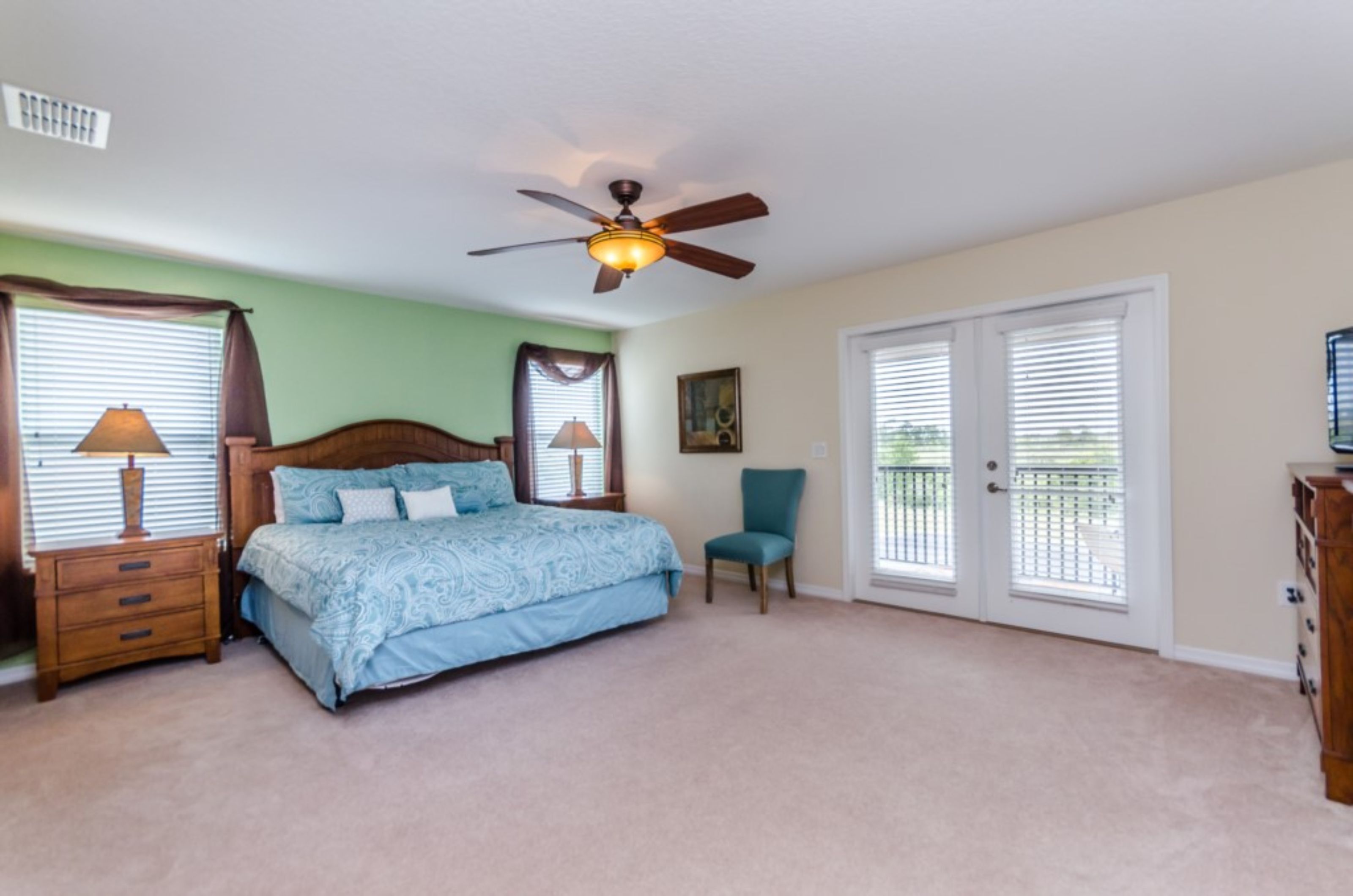 Ein Schlafzimmer mit Bett, Deckenventilator, Stuhl und Kommode.
