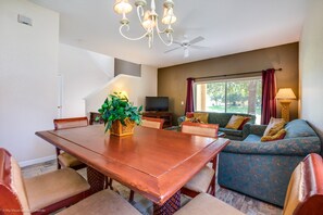 A spacious living area with a wooden dining table, comfortable seating, a television, and a large window with curtains. - 2735calab (Davenport)