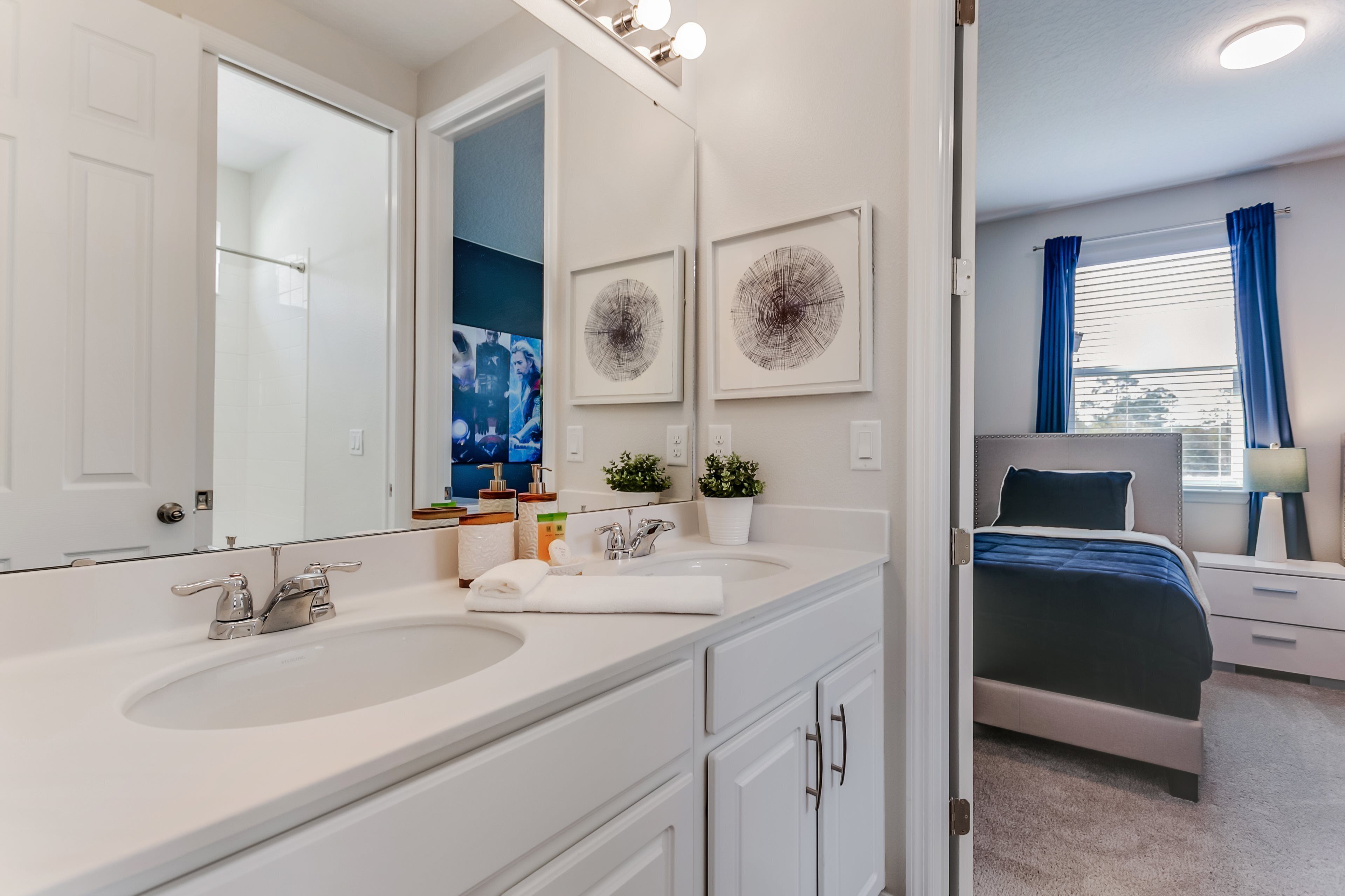 Un bagno moderno con doppio lavabo, uno specchio grande e una doccia.
