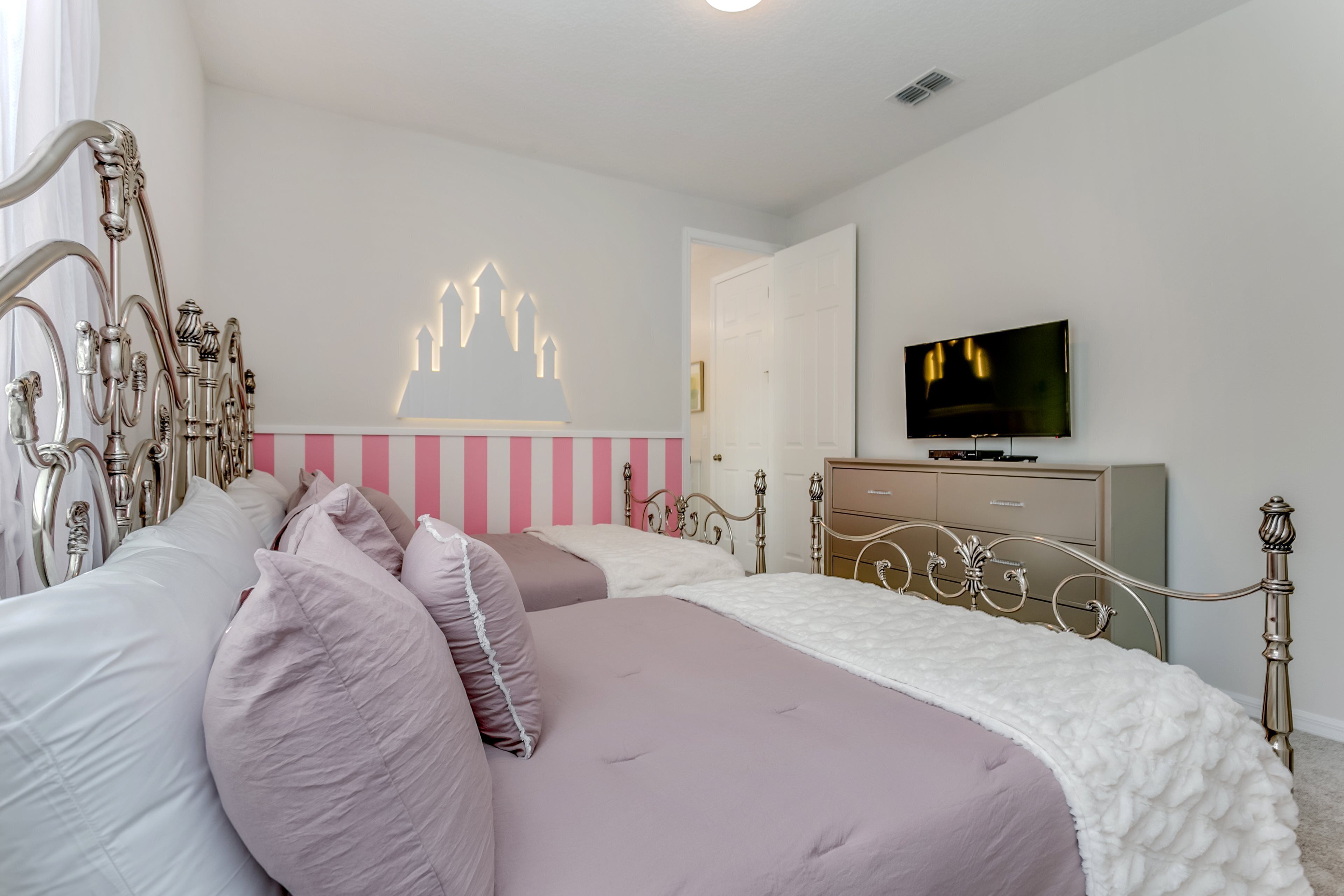 A bedroom with two beds, a TV, and a decorative wall piece.