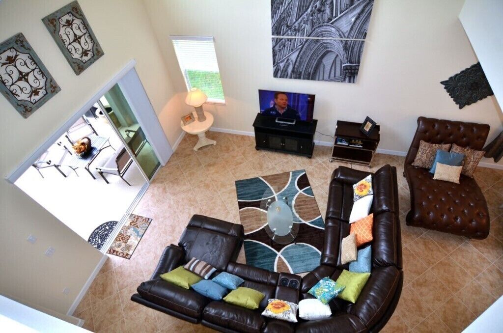 Sala de estar com sofá seccional, mesa de centro, televisão e obras de arte decorativas na parede.
