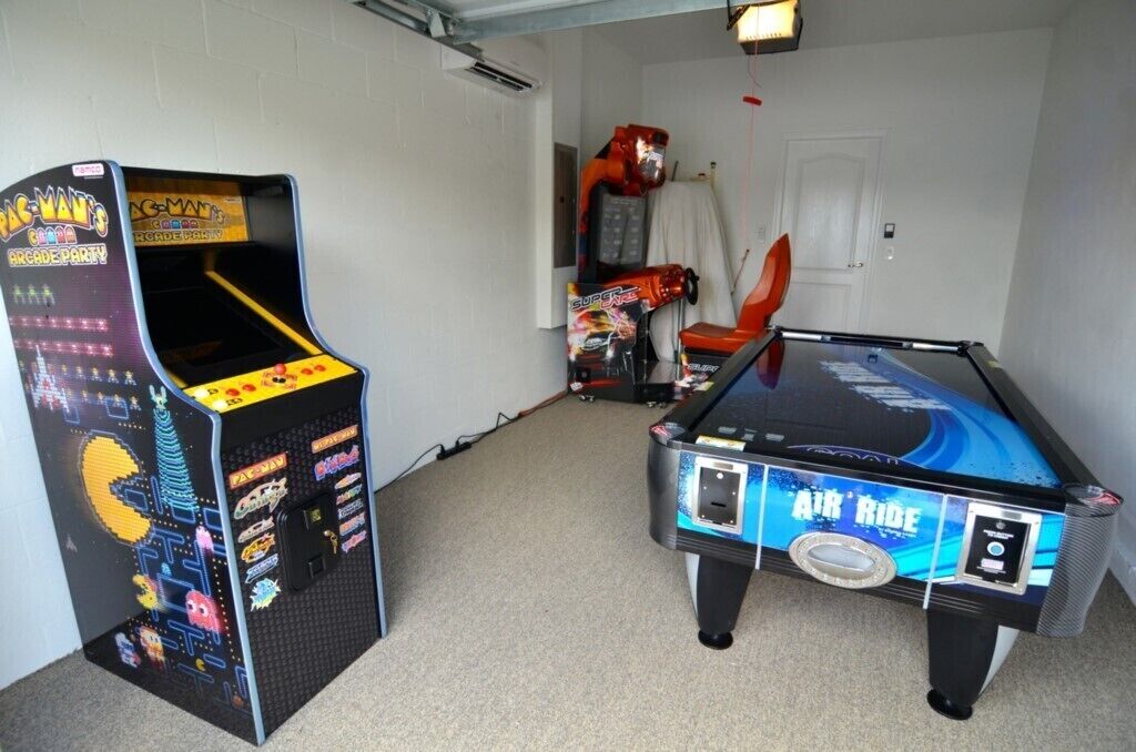 A room with a Pac-Man arcade machine and an Air Ride pool table.