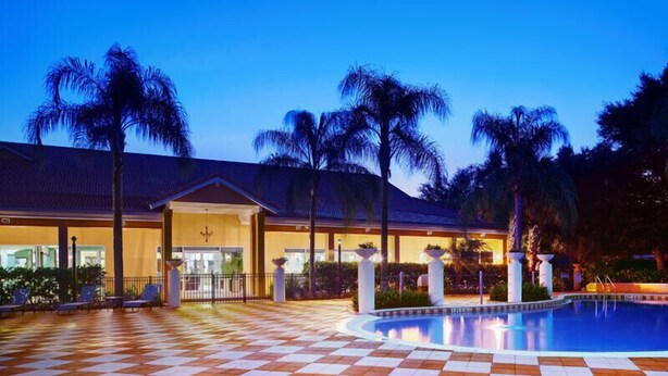 A hotel with a pool, palm trees, and a checkered floor.