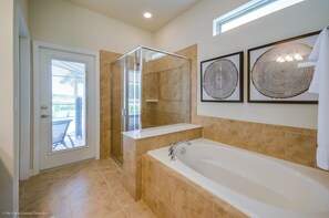 Ein modernes Badezimmer mit einer gläsernen Duschkabine, einer großzügigen Badewanne und zwei gerahmten Wandbildern.