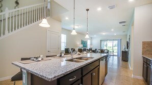 A spacious kitchen with a large island, granite countertops, and pendant lighting.