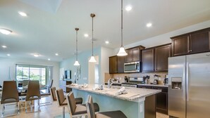 A modern kitchen with a central island, stainless steel appliances, and pendant lighting.