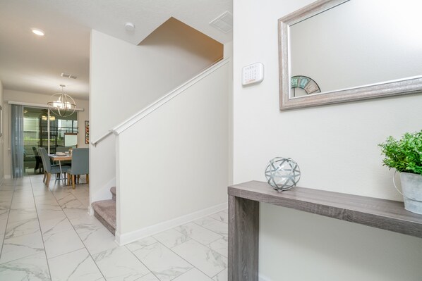 A modern interior with a staircase, a dining area, and a console table with a plant.