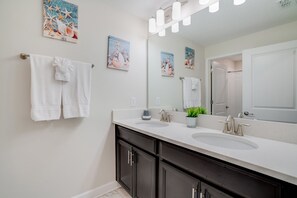 A modern bathroom with two sinks, dark cabinets, and decorative wall art. - Cozy 4 Bed 3 Ba Champions Gate Pool Home1566pd (Davenport)