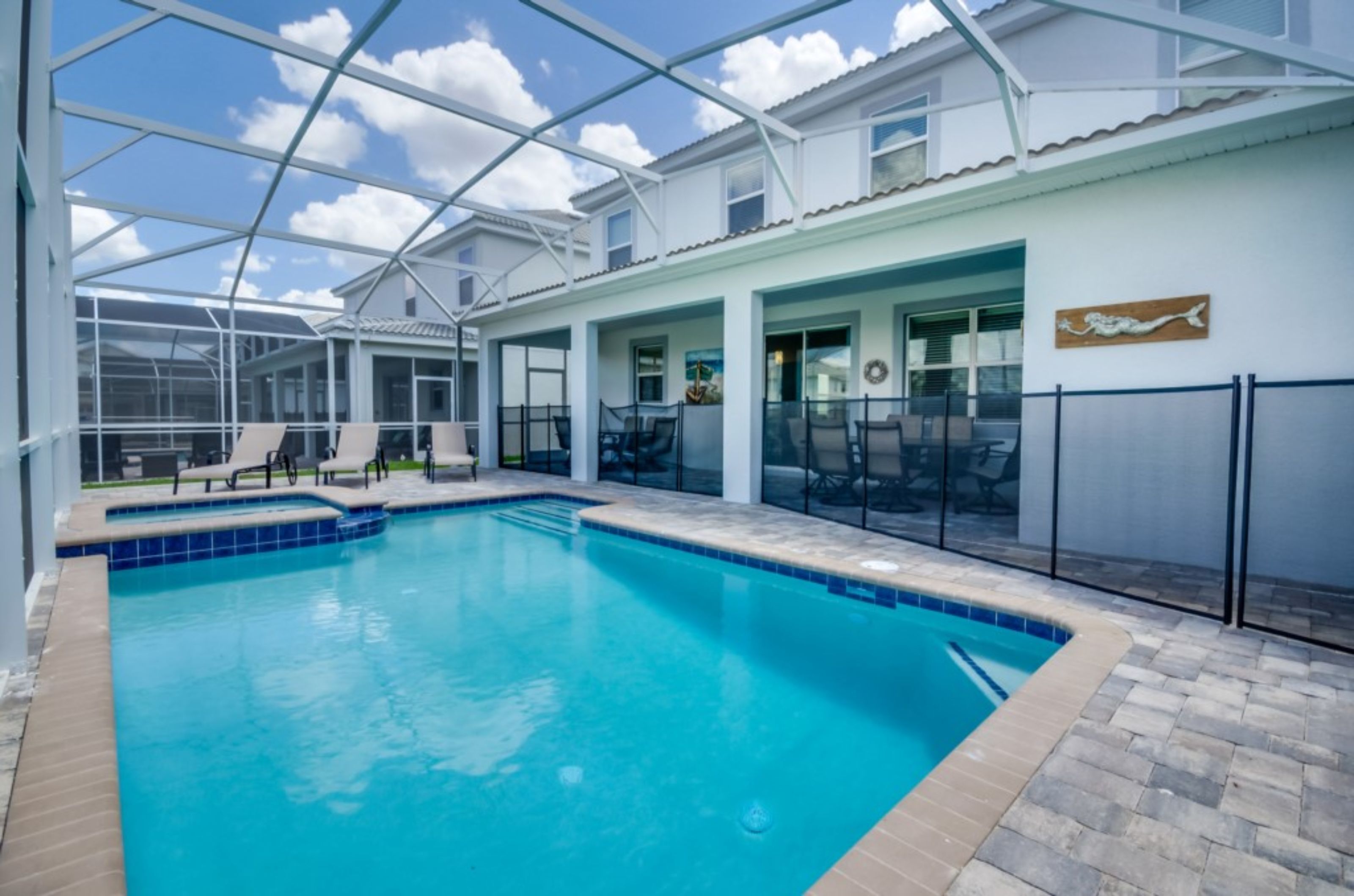 A swimming pool with a glass enclosure, lounge chairs, and a view of the sky.