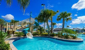 A swimming pool with a water slide, surrounded by palm trees and a clear blue sky. - 9039dld00 (Davenport)