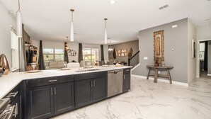 A spacious kitchen with a large island, dark cabinets, and a marble floor. - 8 Bdrm Champions Gate Villa (Kissimmee)