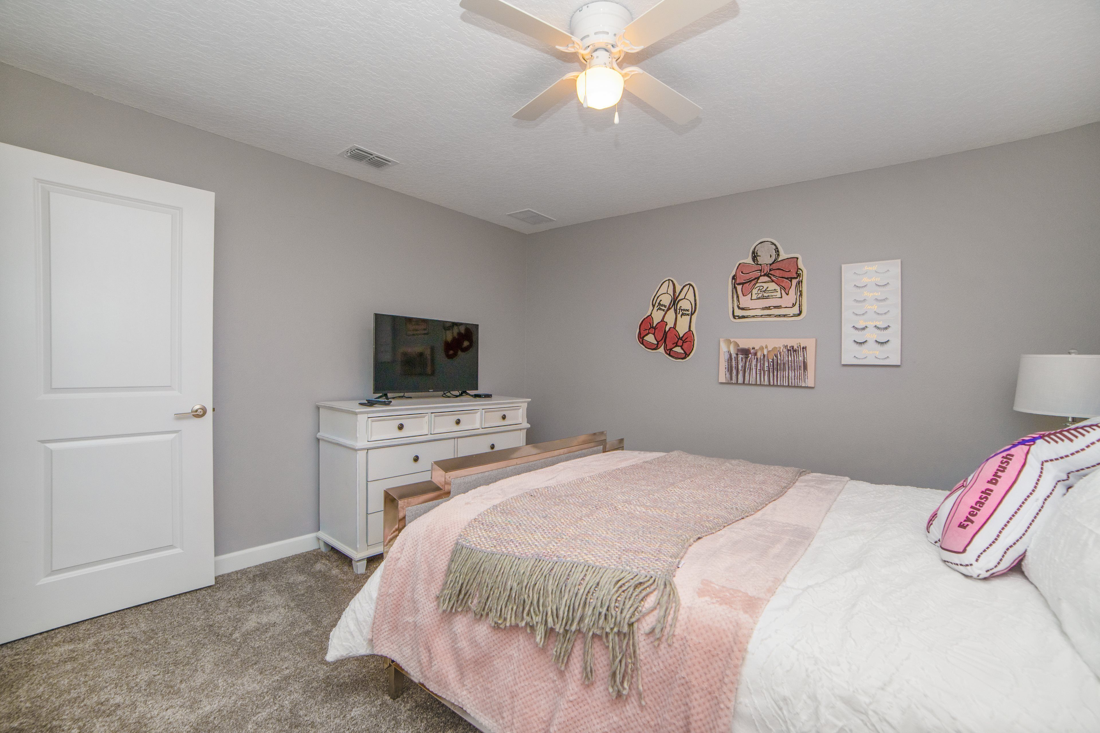 A bedroom with a bed, a dresser, a television, and wall decorations.