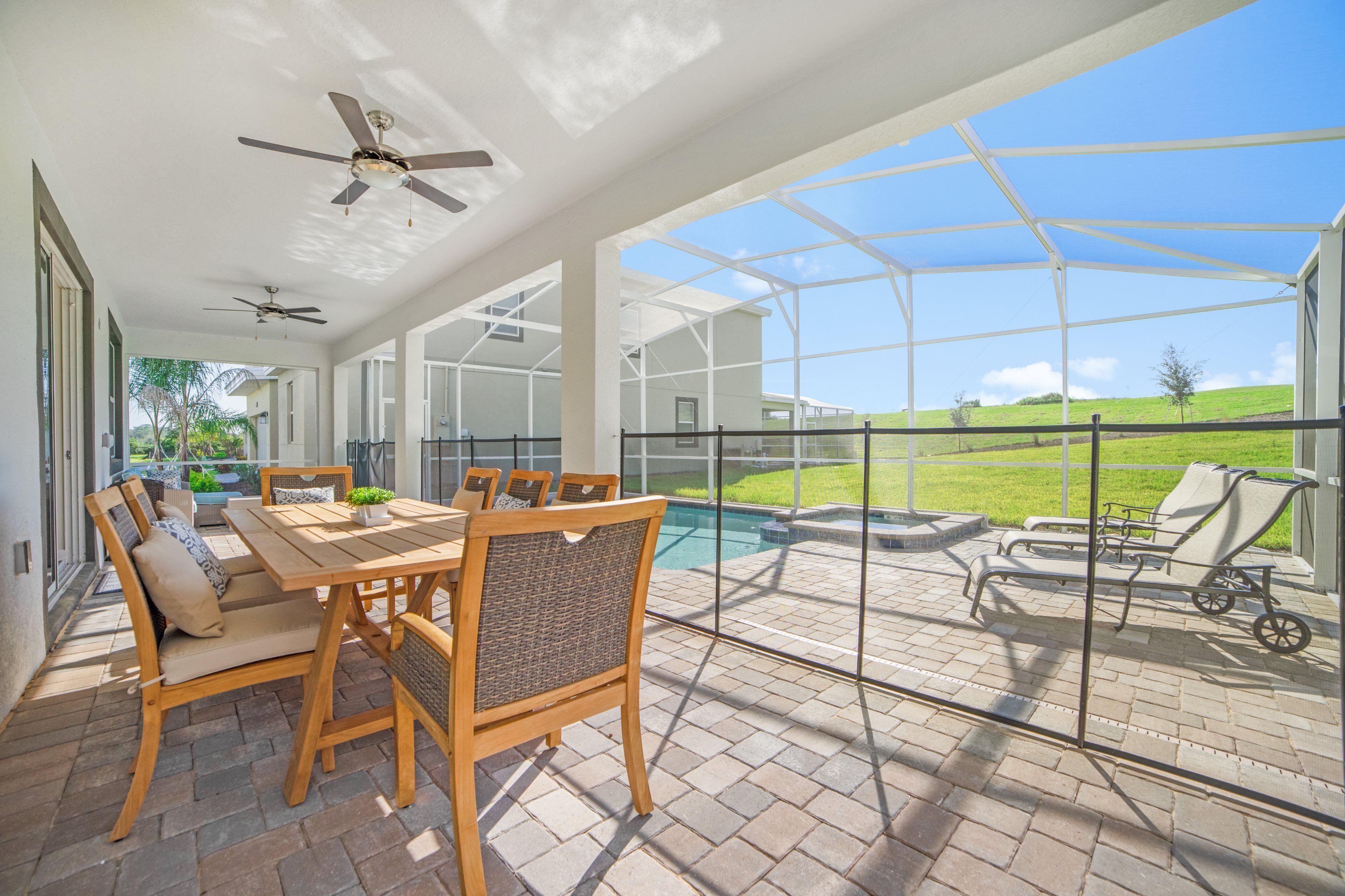 A covered patio with a pool, outdoor furniture, and a view of the surrounding landscape.