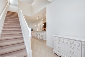 A staircase leading to a kitchen area with white bar stools and a white dresser. - 1804gobi Amazing 7 Bedroom 5 Bathroom Windsor (Kissimmee)