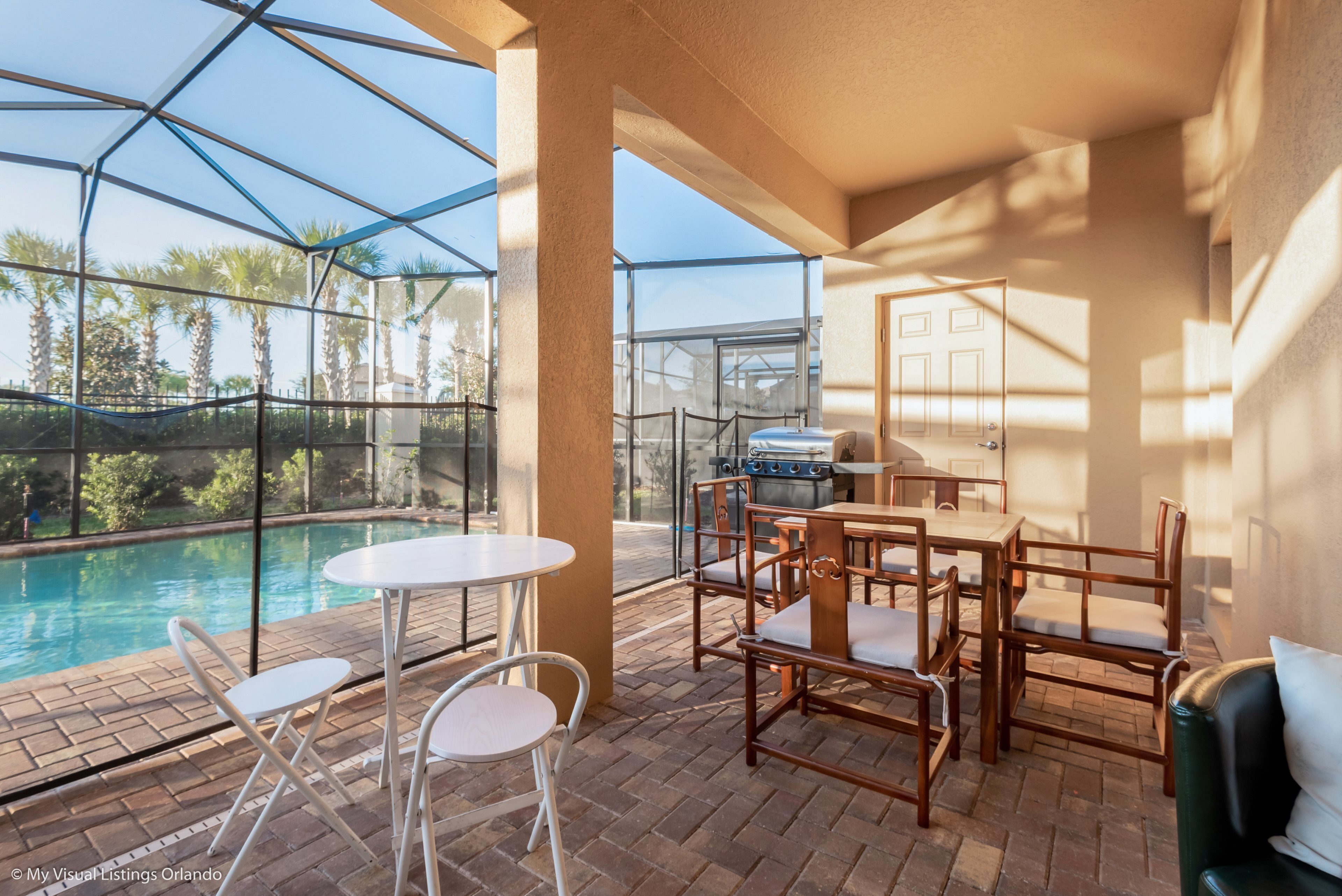 Un patio extérieur couvert avec une piscine, des meubles en bois et un espace barbecue.