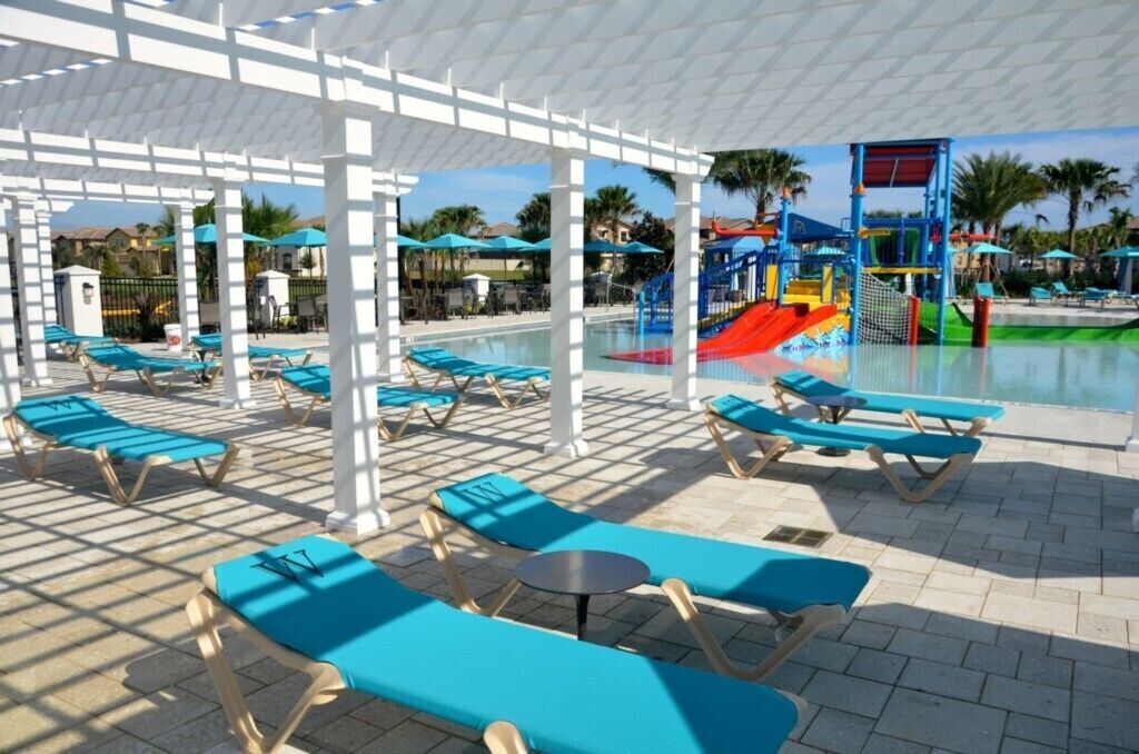 Un área junto a la piscina con tumbonas y un parque infantil.