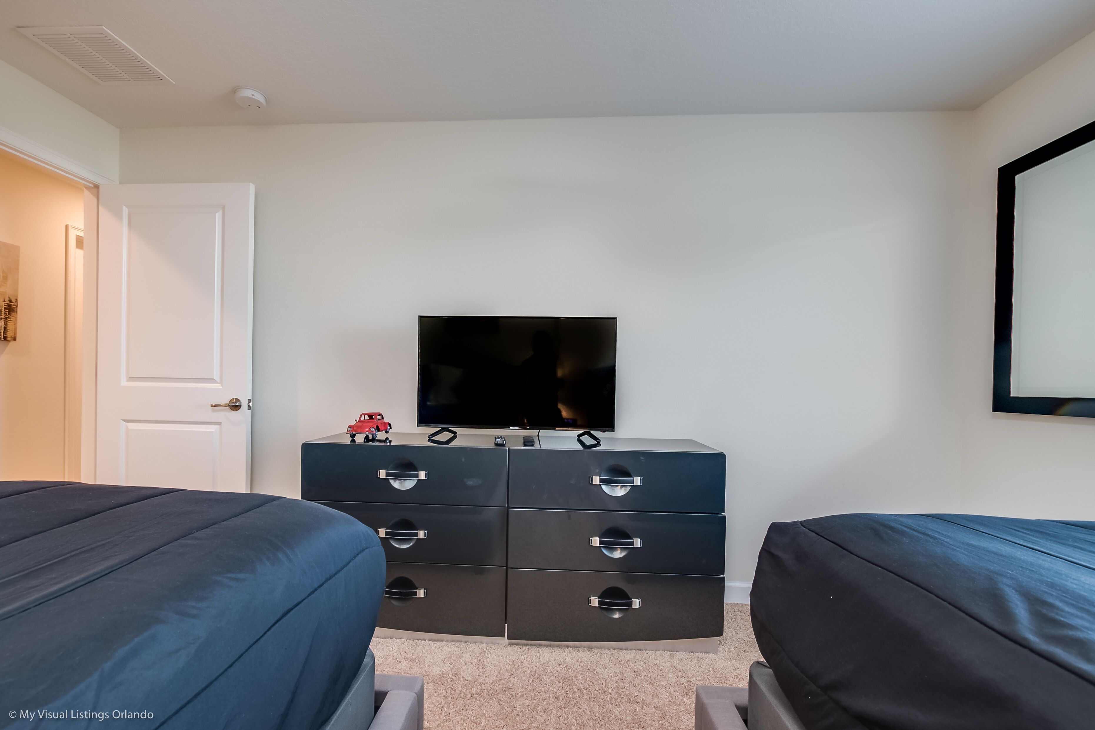 A bedroom with two beds, a TV, and a dresser.