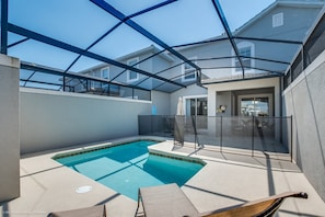 Une piscine dotée d’un toit en verre, entourée d’une clôture, et un hamac.