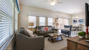 A living room with a sofa, coffee table, and a dining area with a table and chairs. - 4 Bedroom Townhouse with Pool (Kissimmee)