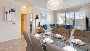 A dining area with a glass table, chairs, and a hanging light fixture. - 3 Bed 3 Bath Pool View High End Corner Condo (Davenport)
