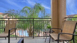 A balcony with two chairs, a small table, and a potted plant. - 3 Bed 3 Bath Pool View High End Corner Condo (Davenport)