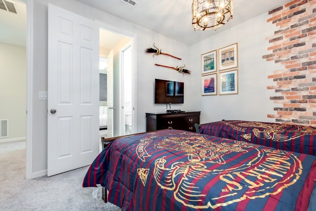 A bedroom with two beds, a TV, and a brick wall.