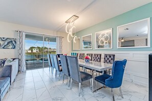 A dining area with a marble-tiled floor, a large dining table with chairs, and a view of a pool through a glass door. - 435ocean (Kissimmee)