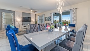 A modern dining area with a large table, comfortable seating, and a view of the outdoors. - 435ocean (Kissimmee)