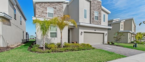 A modern two-story residential building with a stone facade, a garage, and a well-maintained lawn.