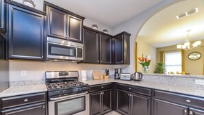 Una cocina moderna con gabinetes oscuros, electrodomésticos de acero inoxidable y encimera de granito.