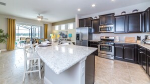 Una cocina moderna con gabinetes oscuros, electrodomésticos de acero inoxidable y una isla grande.