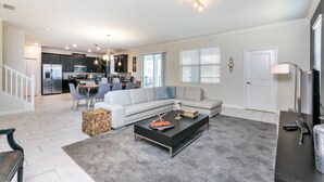 A spacious living room with a black coffee table, a gray sofa, and a dining area in the background. - 6 Bedroom Resort Villa With Spa (Davenport)