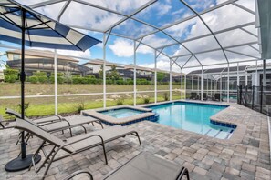 Une piscine couverte dotée de chaises longues et d’un jacuzzi, le tout entouré d’une terrasse en briques.