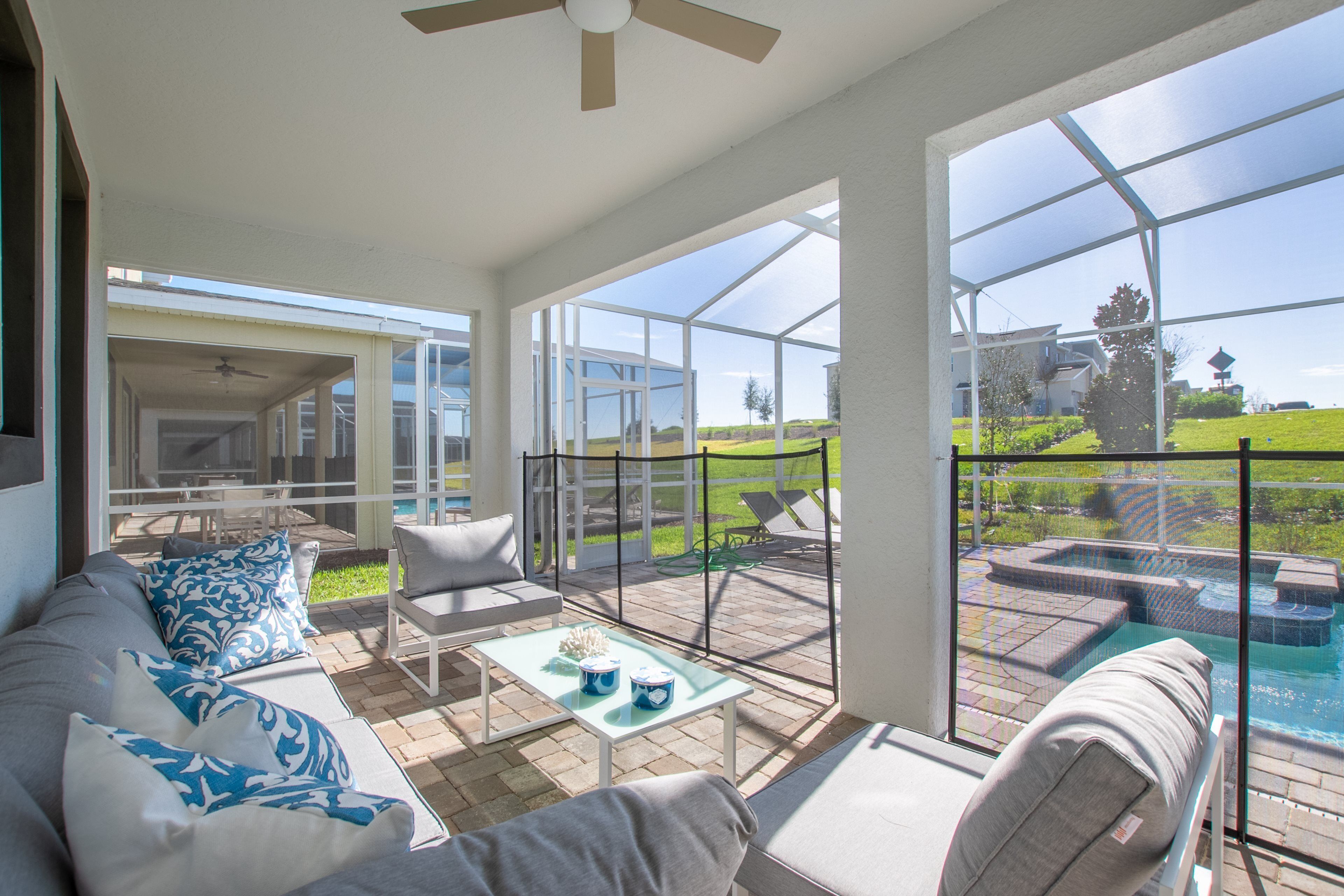 A spacious patio area with a pool, outdoor furniture, and large windows offering views of the surrounding landscape.