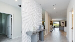 A modern interior with a central console table, a patterned wall, and a view into a living area. - 9 Bedroom Champions Gate Villa (Kissimmee)