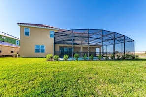 A modern house with a large glass enclosure, a well-maintained lawn, and a neighboring building. - Cool and Modern 9 Bed 7 Ba Villa Pool & Spa 6160boa (Davenport)