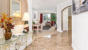 A spacious living area with a glass coffee table, a dining table with chairs, a sofa, and a staircase leading to another level. - 215glen Amazing Newly Decorated 5 Bedroom (Davenport)