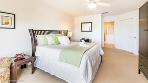 A bedroom with a bed, a nightstand, a chair, a ceiling fan, a door, and a wall-mounted mirror. - 215glen Amazing Newly Decorated 5 Bedroom (Davenport)