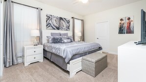 A bedroom with a bed, nightstands, a bench, a ceiling fan, and artwork on the walls. - 9085hs (Davenport)