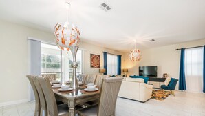 A dining area with a table set for four, a sofa, and a TV in the living room. - 9085hs (Davenport)