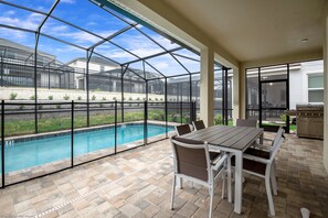 A covered patio with a pool, outdoor seating, and a view of the neighborhood. - 1780spp New 7 Bedroom 5 Bathroom Solara Villa (Kissimmee)