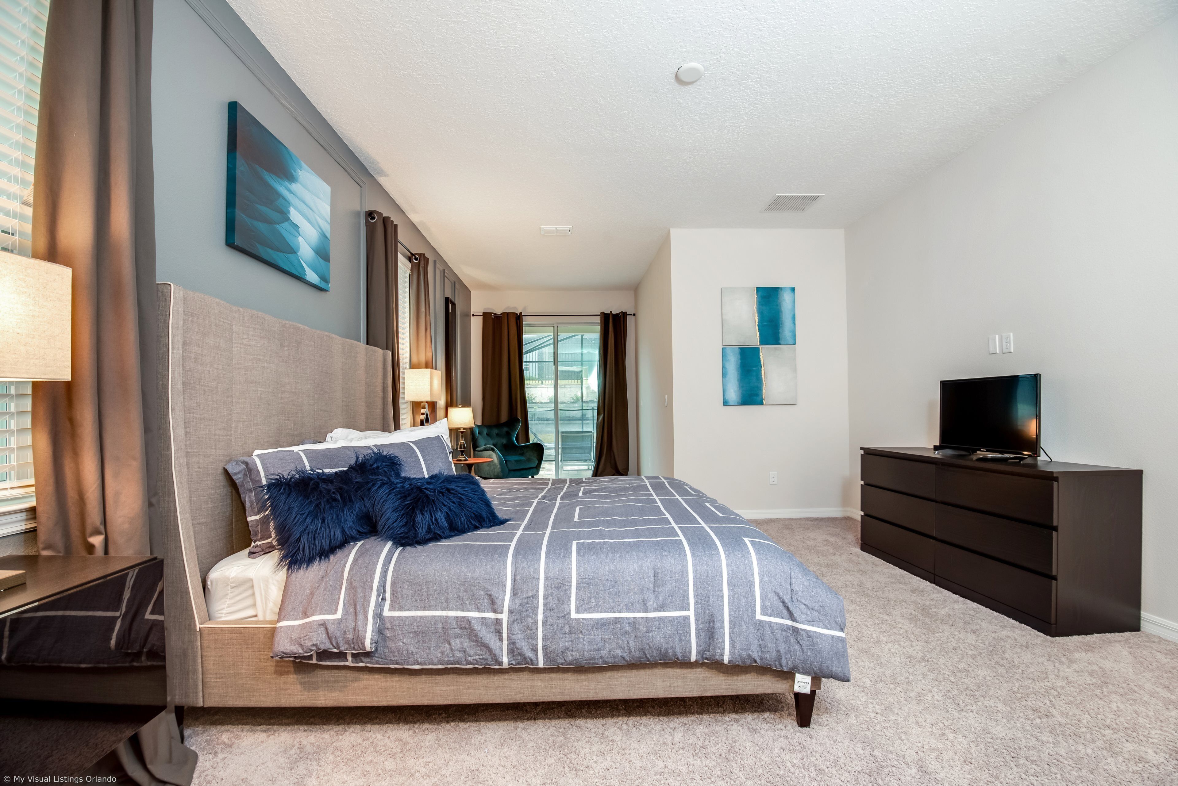 Une chambre à coucher moderne avec un grand lit, une télévision et une commode.