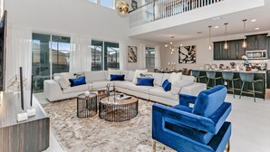 A spacious living area with a sectional sofa, a round coffee table, and a blue armchair.