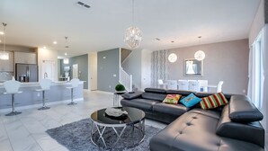 Ett modernt vardagsrum med en svart lädersoffa, ett runt soffbord och en grå, lurvig matta.