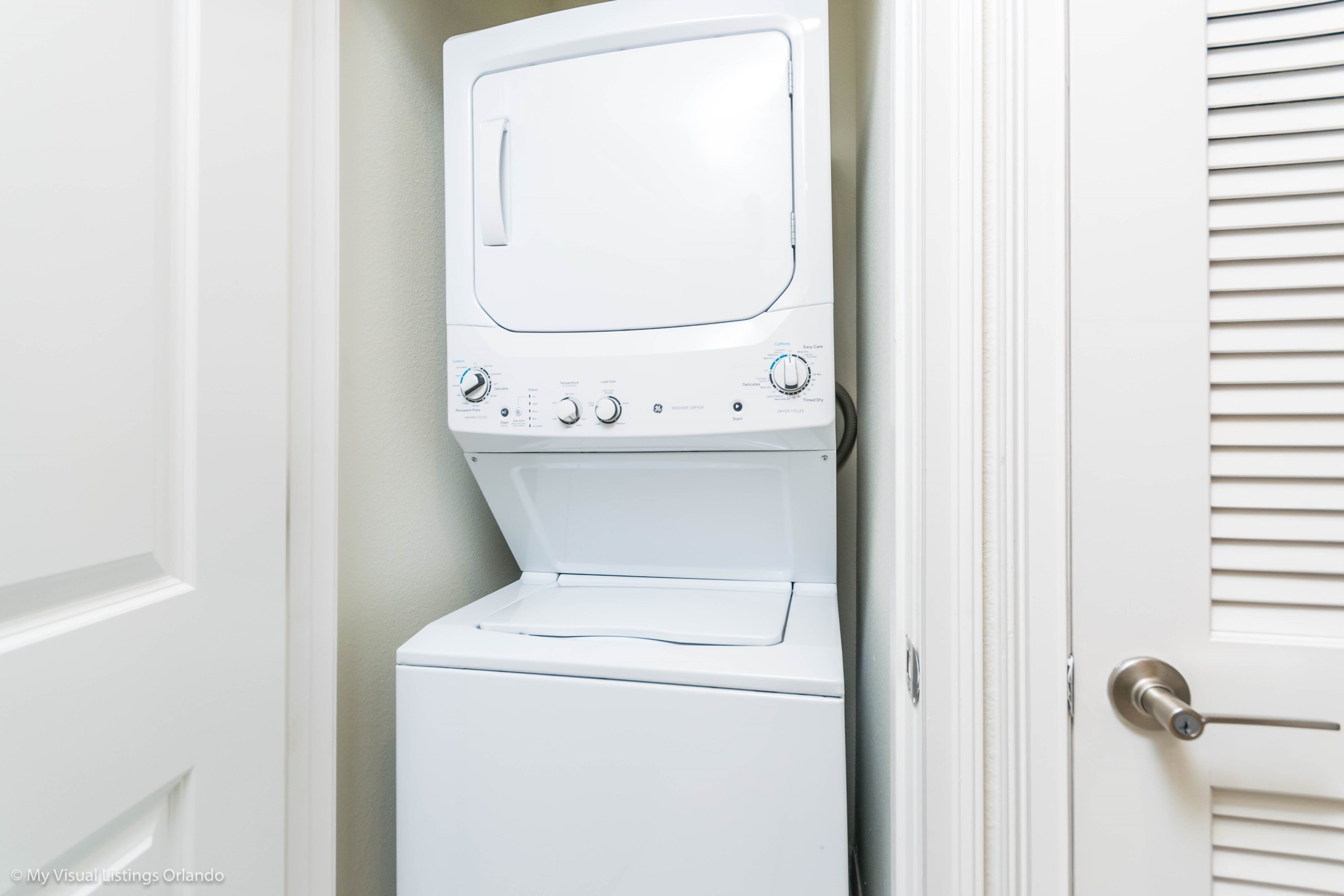A white stacked washer and dryer unit with control knobs and a door handle.