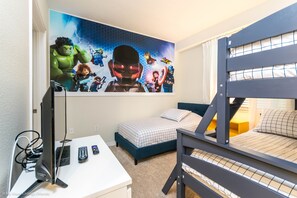 Une chambre avec un lit superposé, un bureau avec un ordinateur et une fresque murale représentant des super-héros.