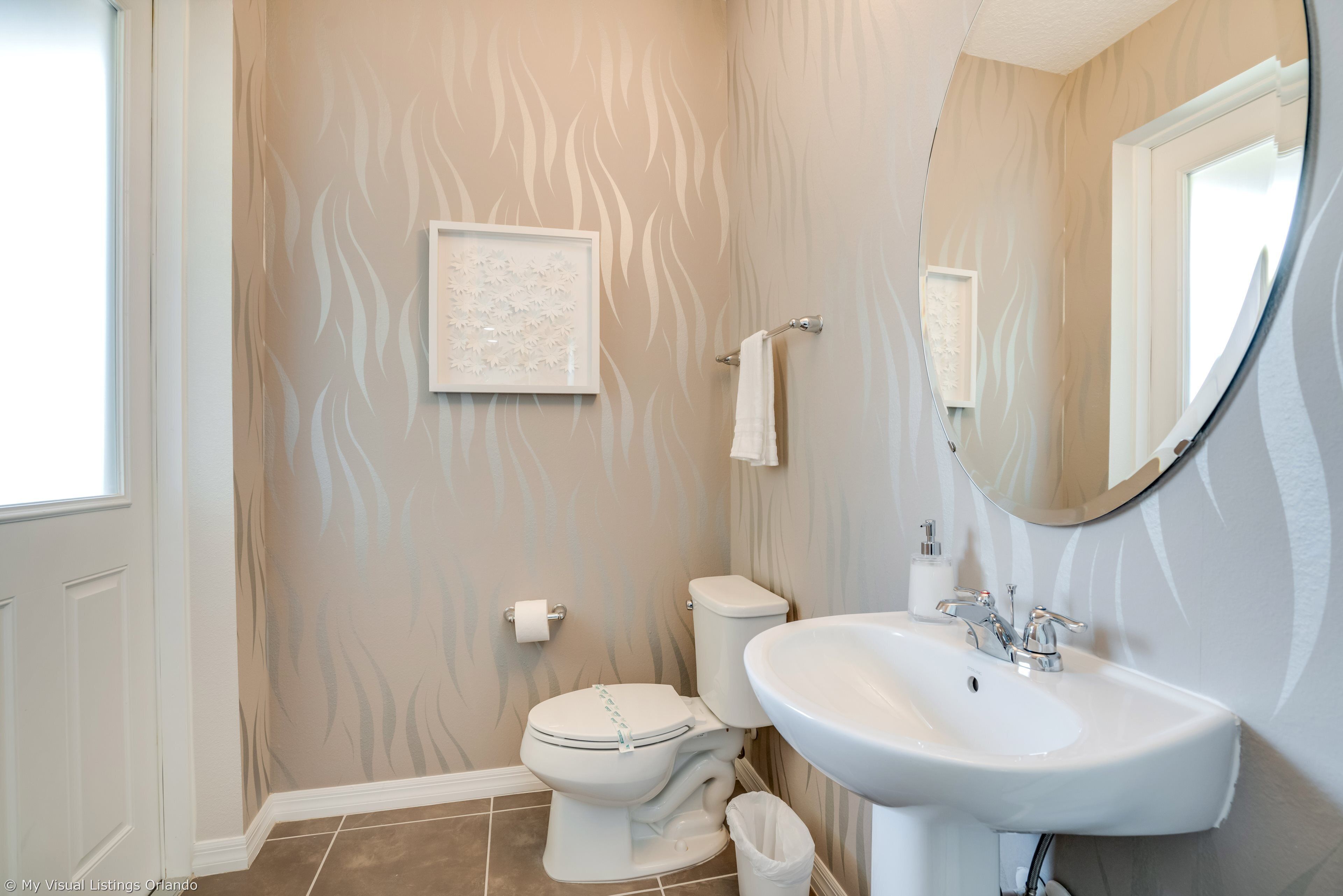 A bathroom with a toilet, sink, and mirror.