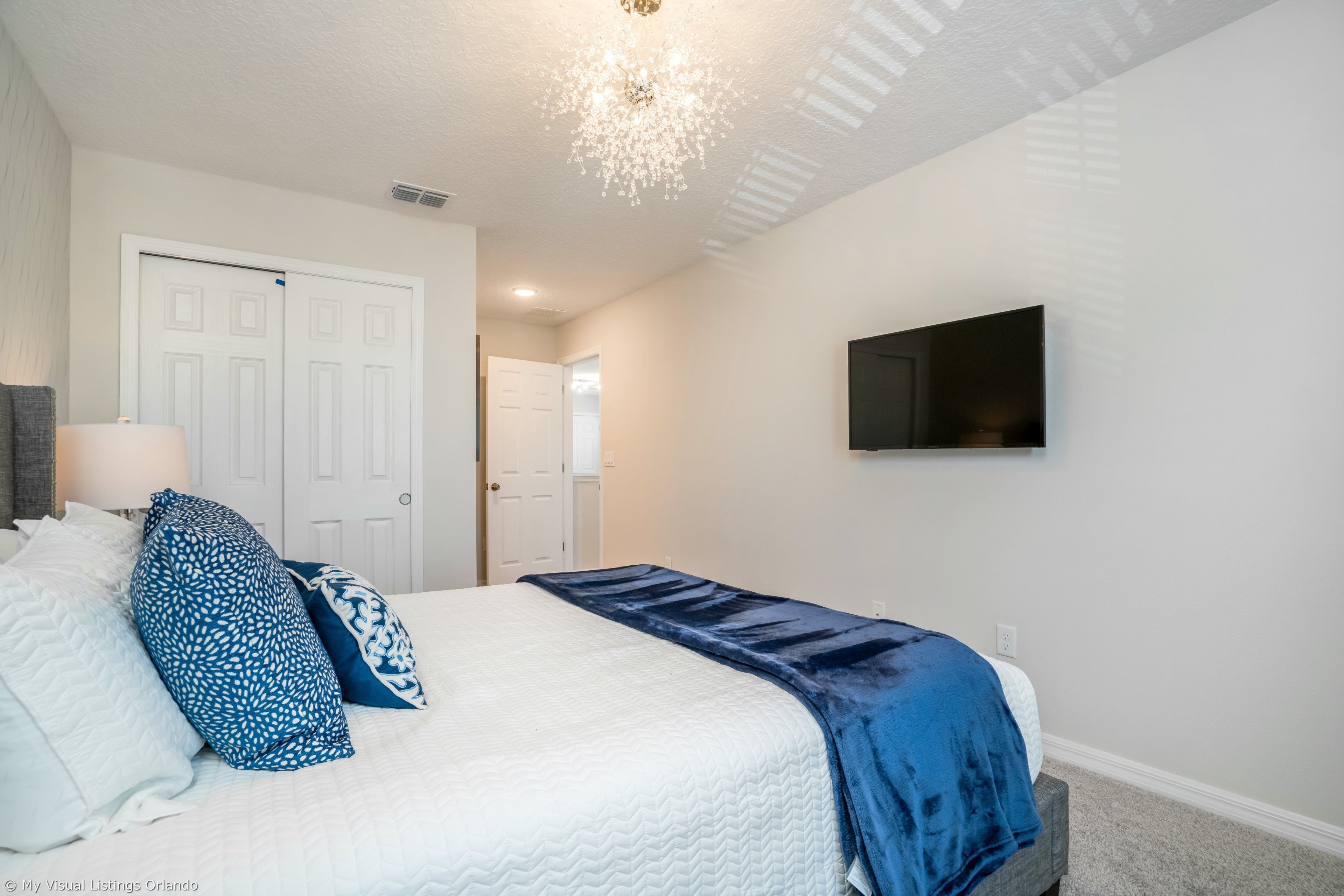Un dormitorio con cama, televisión y puerta.