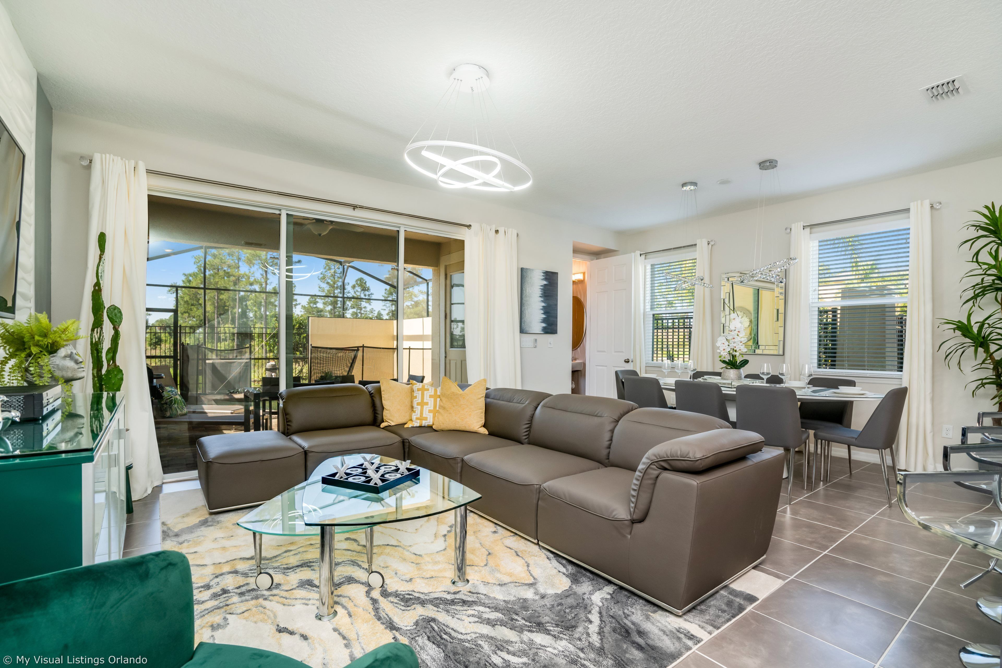 A modern living room with a sectional sofa, glass coffee table, and a dining area with a table and chairs.
